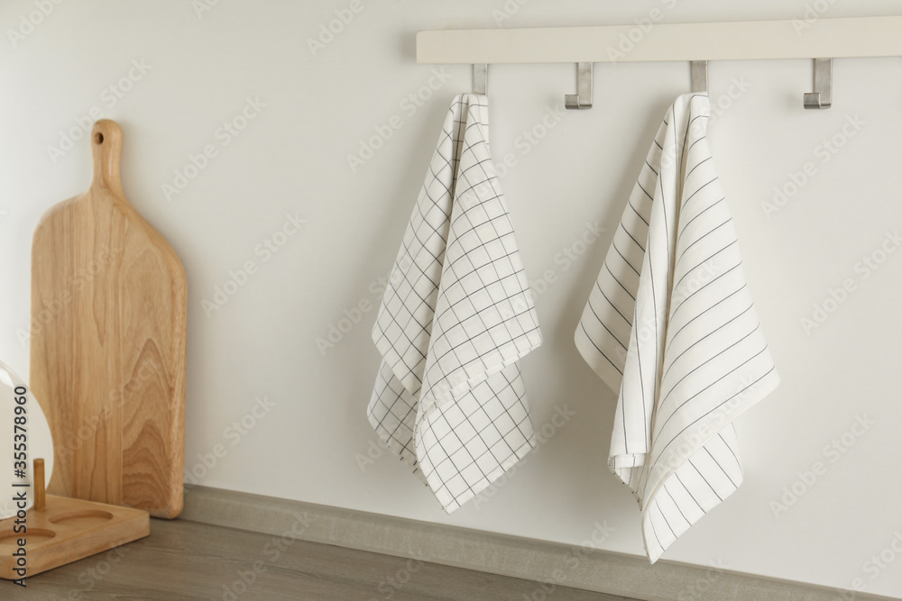 Different kitchen towels hanging on hook rack indoors - obrazy, fototapety, plakaty 