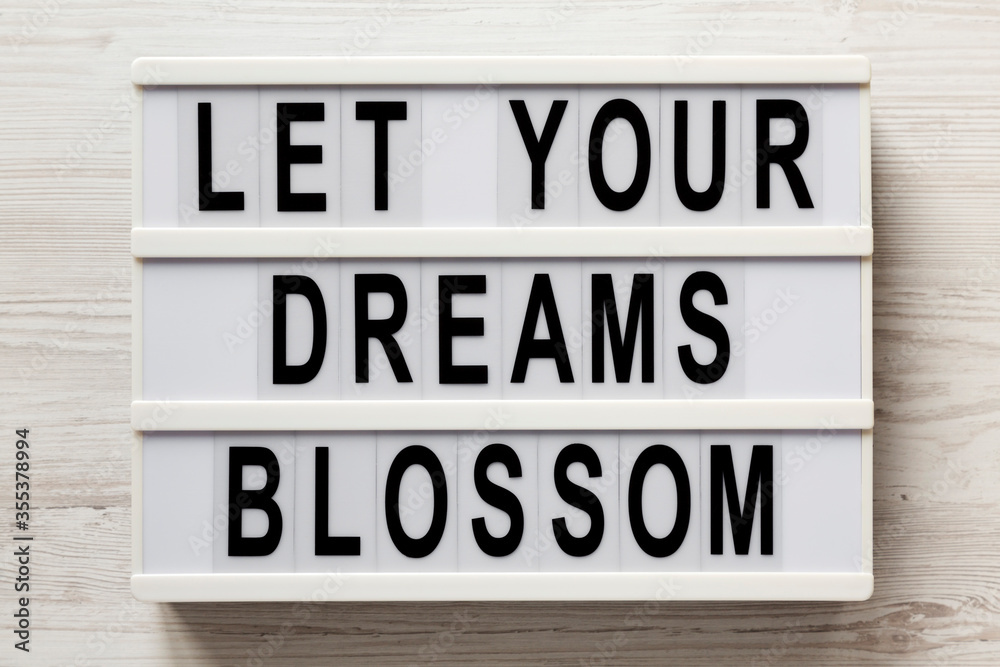 'Let your dreams blossom' on a modern board on a white wooden background, top view. Flat lay, overhead, from above. 'Let your dreams blossom' on a modern board on a white wooden background, top view. Flat lay, overhead, from above.