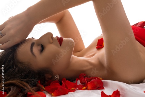 Sexy Brunette lying in bed with rose petals