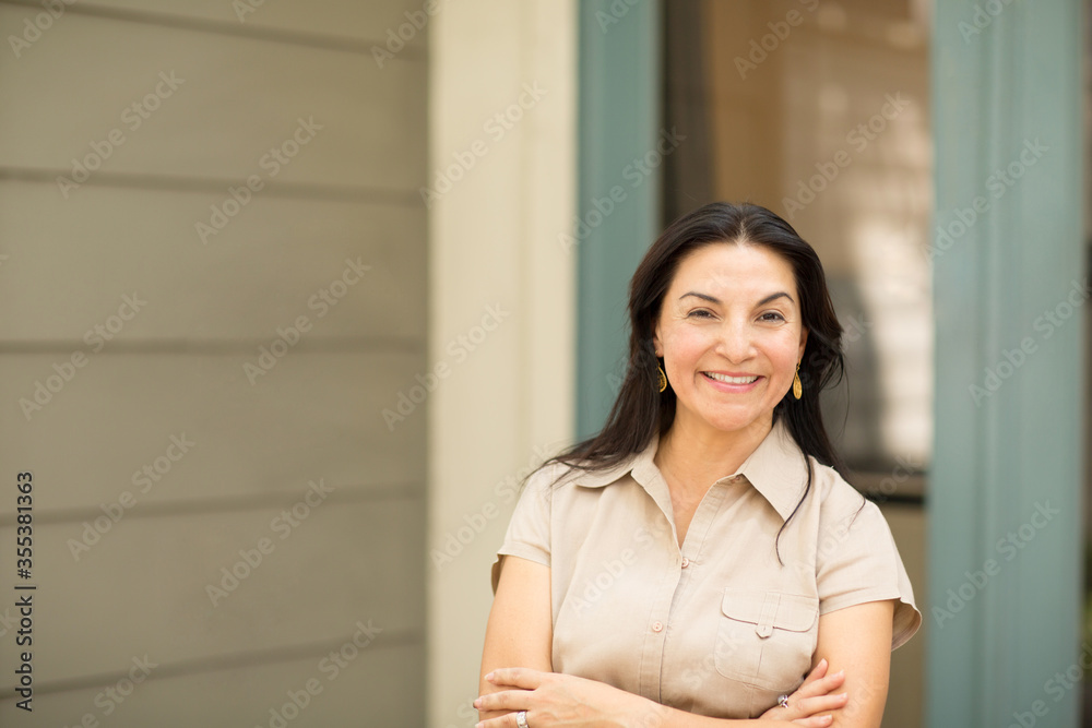 Happy Hispanic woman smiling and standing outside.