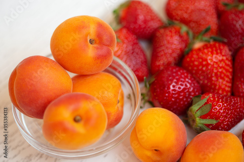 vase with apricots and fresh strawberries