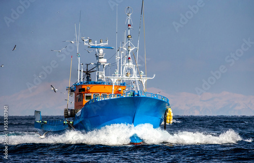 Fototapeta Fishing boat returns after fishing to its port