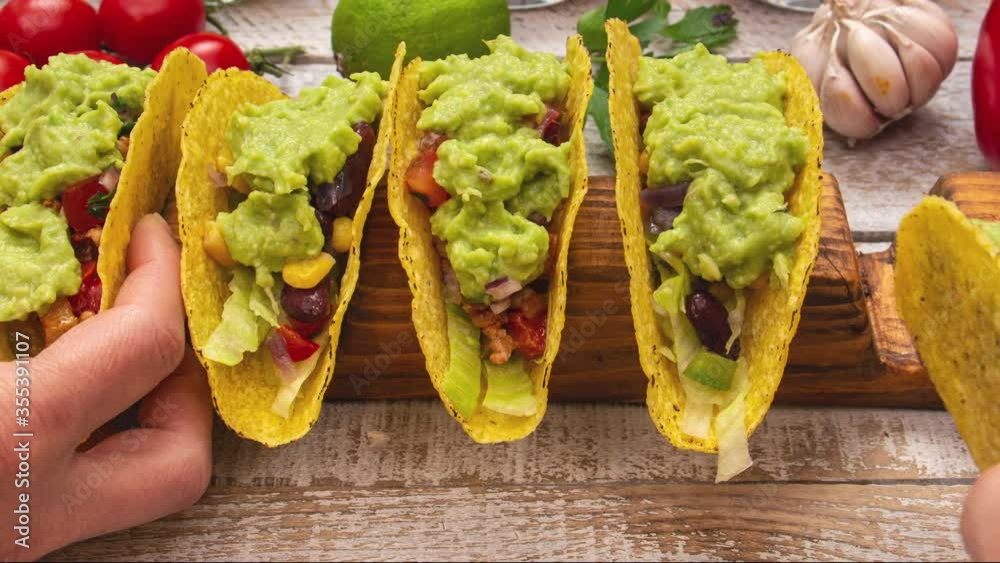 Making delicious hard shell tacos, stuffing and assembling the popular mexican dish - hands reaching to get a savory bite - close up, stop motion animation