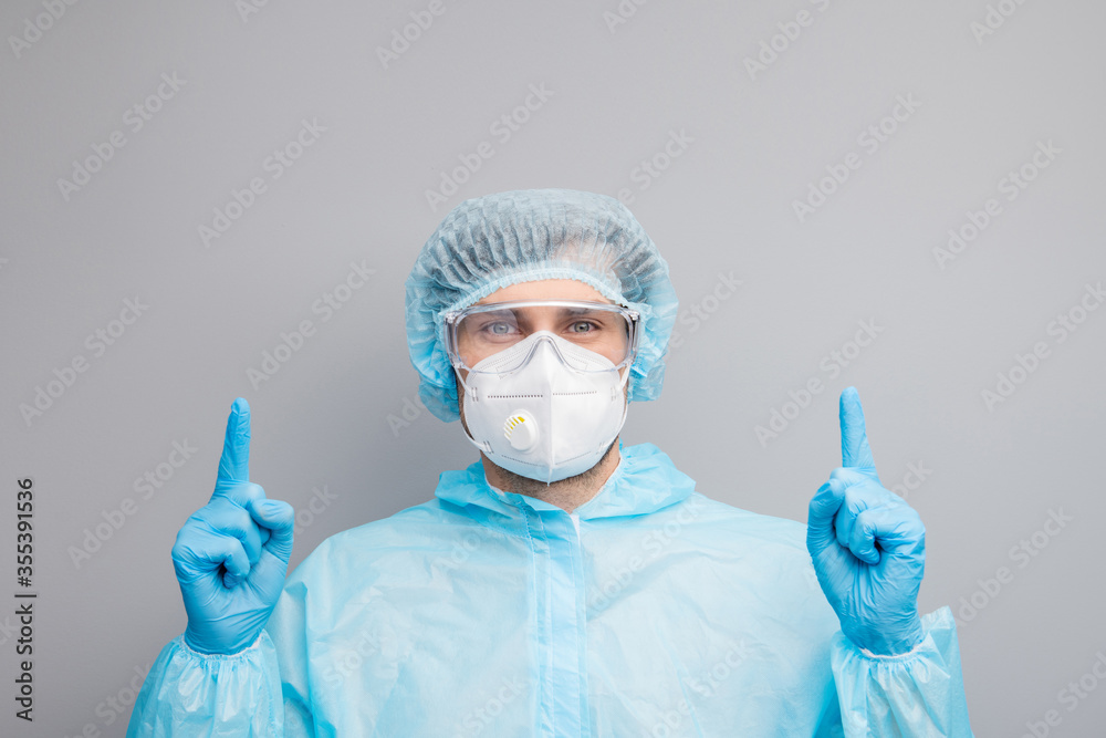 Closeup photo of guy expert doc virology center directing fingers up empty space remind vaccination time wear mask hazmat blue uniform suit protective goggles isolated grey color background Closeup photo of guy expert doc virology center directing fingers up empty space remind vaccination time wear mask hazmat blue uniform suit protective goggles isolated grey color background
