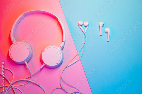 Old headphones and wireless headphones on a colored background. Minimalism concept. photo