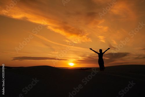 A woman standing against the backdrop of the setting sun