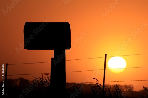 Kansas country Mailbox silhouette at sunset on a farm road.