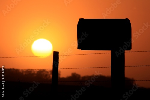 Kansas country Mailbox silhouette at sunset on a farm road.