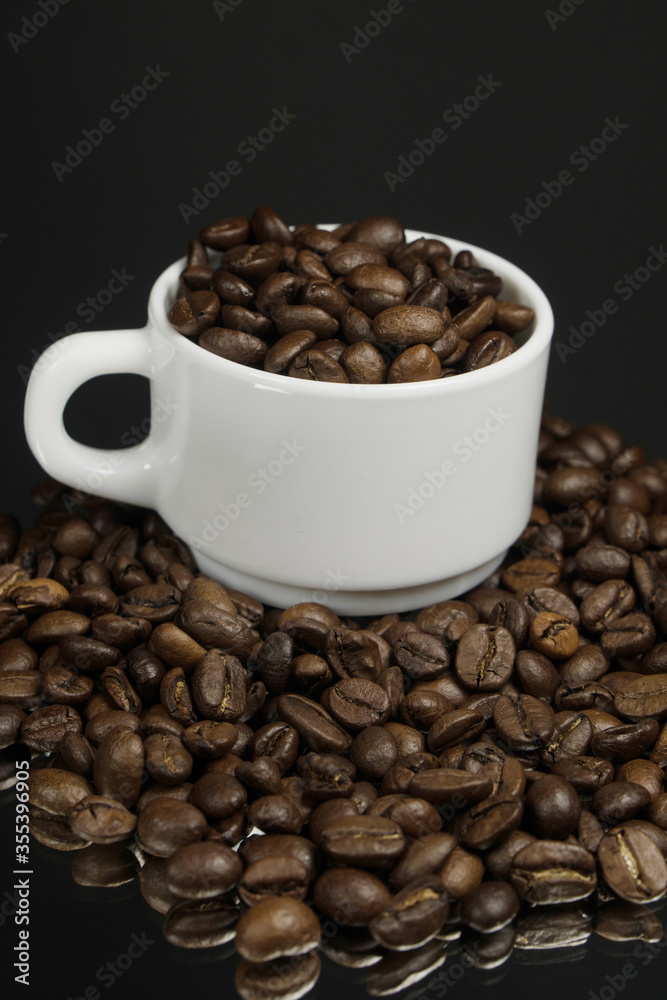 White mug with coffee grains sprinkled with coffee grains on a background