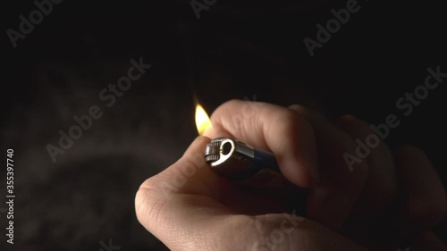 Hand Of A Man Igniting The Lighter And Glowing In The Dark Background.  - close up shot photo