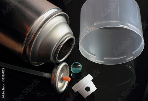 Aerosol can in component parts on black background