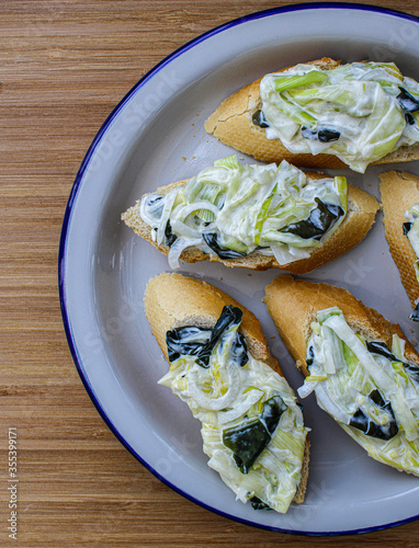  Basque pintxos canape style served in a sharing plate. Leek, seaweed and mayonnaise salad over a piece of bread. Vegan pintxo. photo