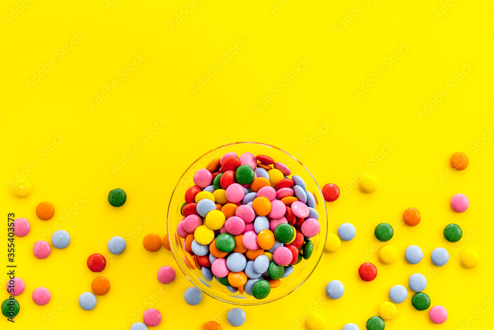 Color candy on yellow table top-down copy space