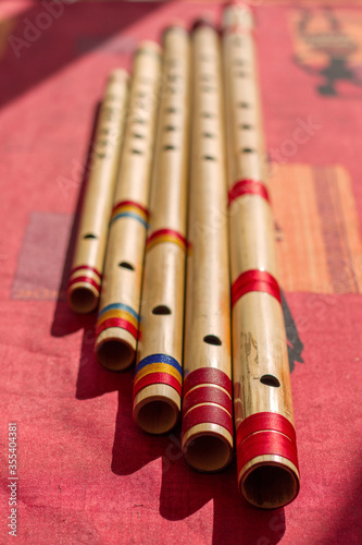 Five north India bamboo flutes on a red table.