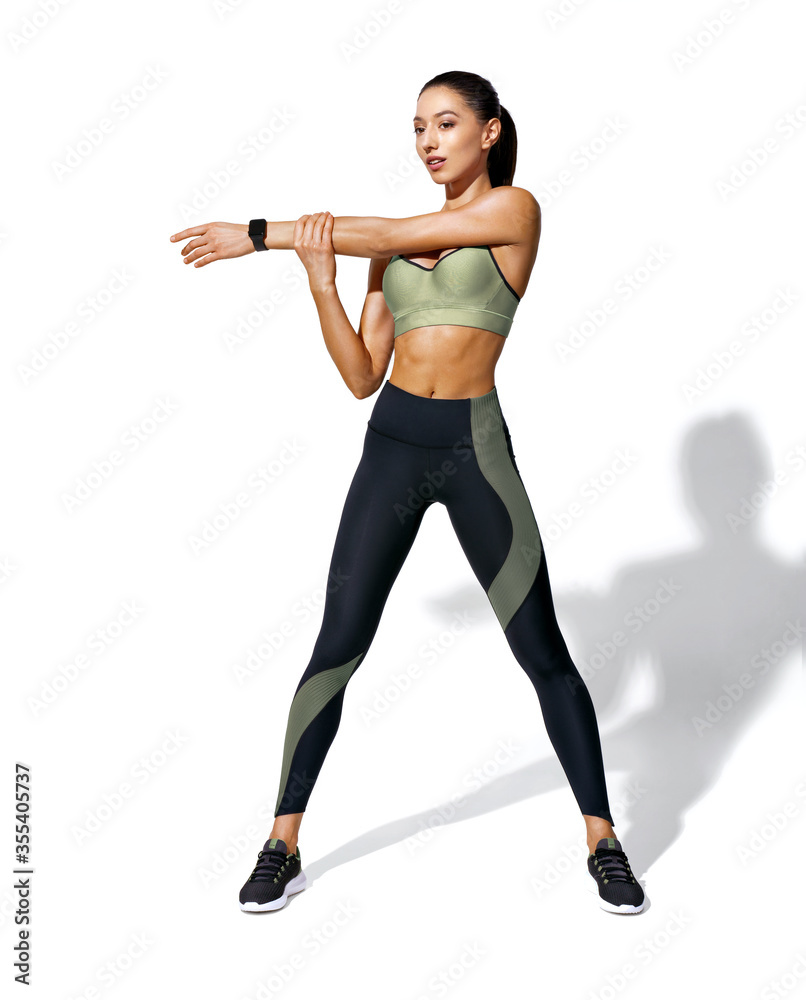 Warming up before training. Photo of sporty girl with perfect body on white background. Strength and motivation Warming up before training. Photo of sporty girl with perfect body on white background. Strength and motivation