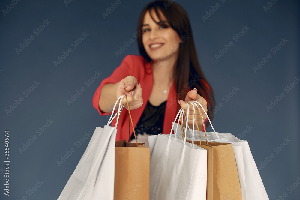 Woman with shopping bags. Lady on a blue background. Famale in a red jacket.