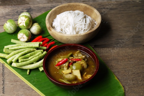 Wooden bowl of Fish organs sour soup and Rice Noodles on banana leaf with vegetables in the kitchen prepare for serving ,Thai local food image for background , selective