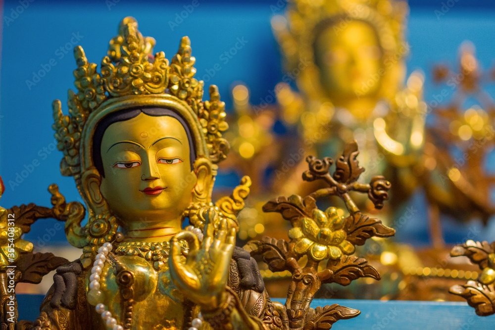 Golden statues showing different buddhist deity Tara at a temple one in front and another one in the background.