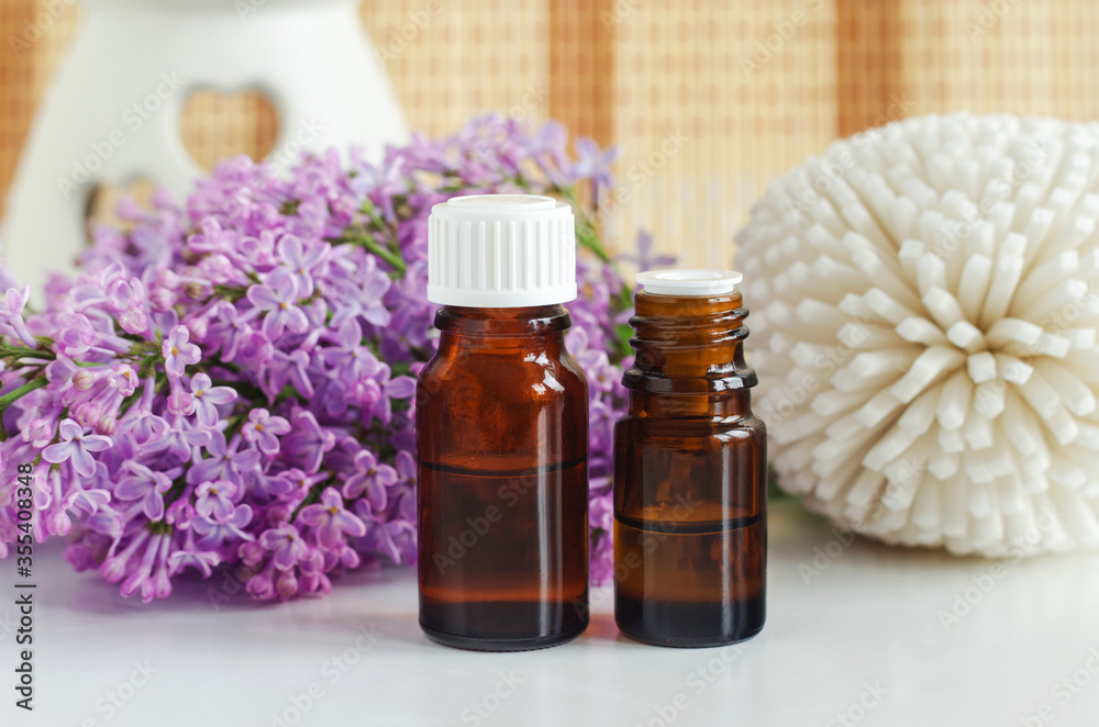 Two small bottles with essential oil (tincture, infusion, perfume) and lilac flowers. Aromatherapy, spa and herbal medicine ingredients. Two small bottles with essential oil (tincture, infusion, perfume) and lilac flowers. Aromatherapy, spa and herbal medicine ingredients.