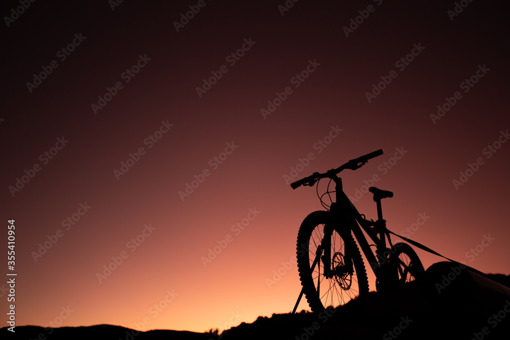 Obraz premium Silhouette of Mountain Bike, Dirt bike on the car roof rack in the countryside at the sunset,Bicycles built for traveling on dirt road.
