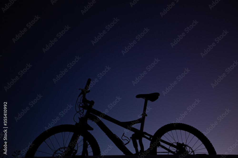 Silhouette of Mountain Bike, Dirt bike on the car roof rack in the countryside at the sunset,Bicycles built for traveling on dirt road.