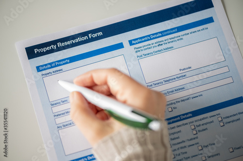 Woman customer filling property reservation form on the table at the office. Rental agreement apartment, house. Close up. Selective focus