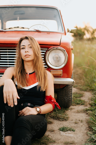 Beautiful young girl posing with vintage red old car.