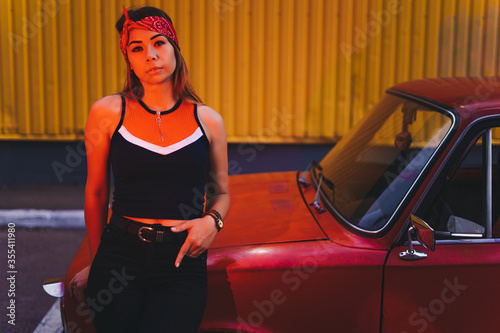 Beautiful young girl posing with vintage red old car.