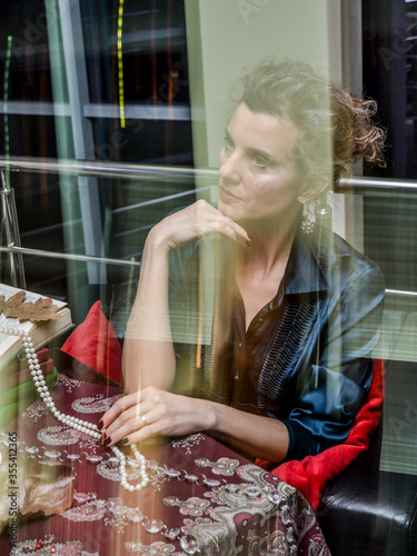 Portrait ashionable and stylish woman in red clothes, located in a dark interior, at a served table with food and utensils. photo