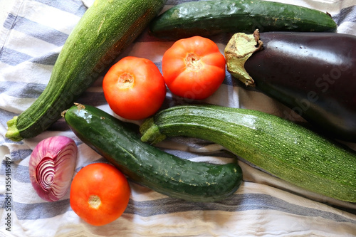 Homegrown summer vegetables on the kitchen counter: tomato, zucchini, cucumber, eggplant and purple onion. Top view.