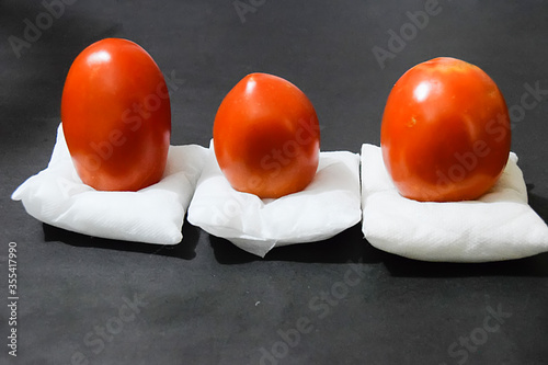 Beautiful red ripe heirloom tomatoes on the tray isolated on black background, Gardening tomato photograph with copy space, Tomatoes isolated on white. photo