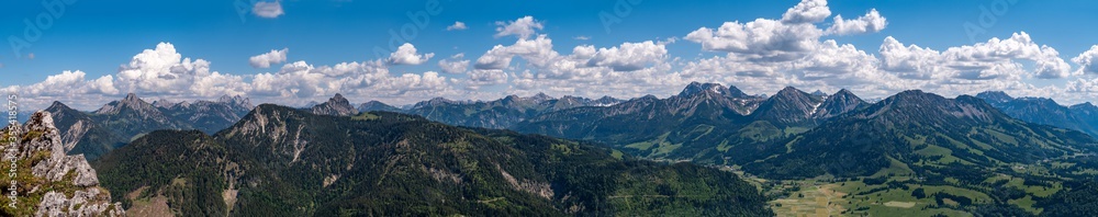 Panorama Tannheimer Berge vom Sorgschrofen bis zum Kühgundkopf bei blauem Himmel und leichten Quellwolken