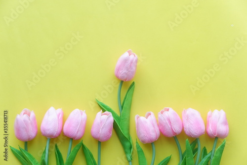 Yellow and pink tulips placed on a wooden table.