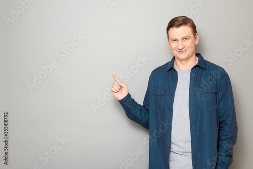 Portrait of happy mature man pointing with index finger at copy space