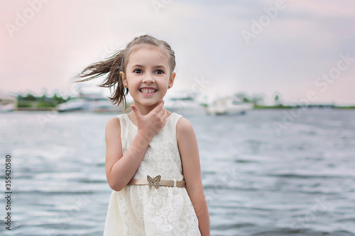 happy little girl on the beach. little girl in a white dress. little girl lying on the grass. little girl walking on the road
