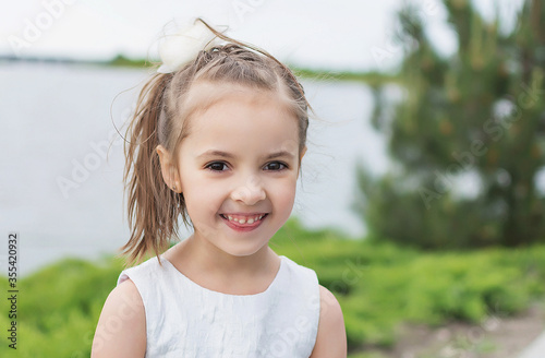 happy little girl on the beach. little girl in a white dress. little girl lying on the grass. little girl walking on the road