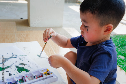 Beautiful little boy having fun painting with water colors