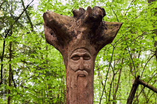 The image of the Slavic deity Veles carved from root of a tree on a neo-Pagan temple in the forest. Kaluzhskiy region, Russia. Veles - the god of cattle breeding, wealth and wisdom photo