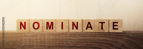 Nominate word on wooden cubes. Concept of words to put forward a candidat for voting or election