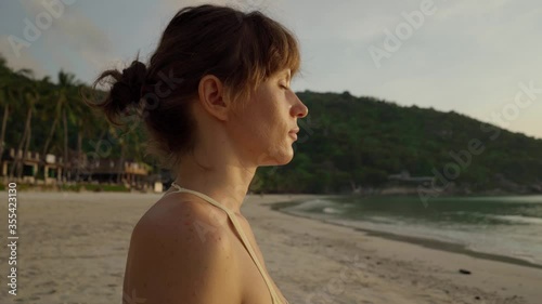 Beautiful young girl doing yoga at sunrise with sea view