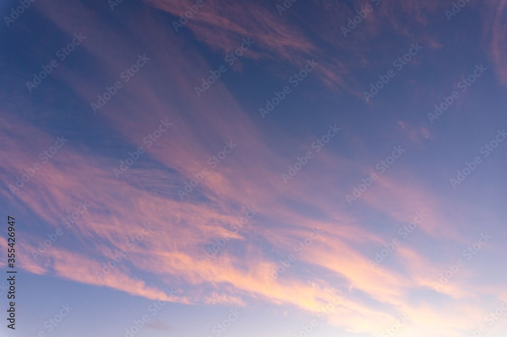 Blue sky with clouds in pink light