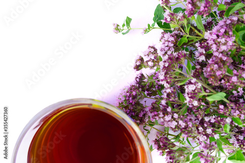 Tea in glass with defocused bouquet of marjoram isolated on white background with free space for text