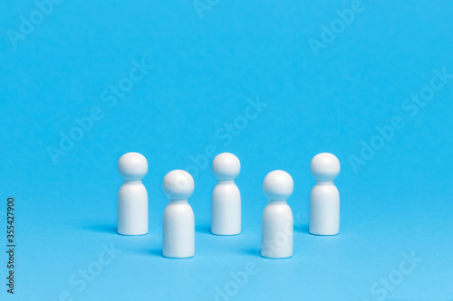 Social distancing conceptual image. White wooden figures of people keep distance on blue background