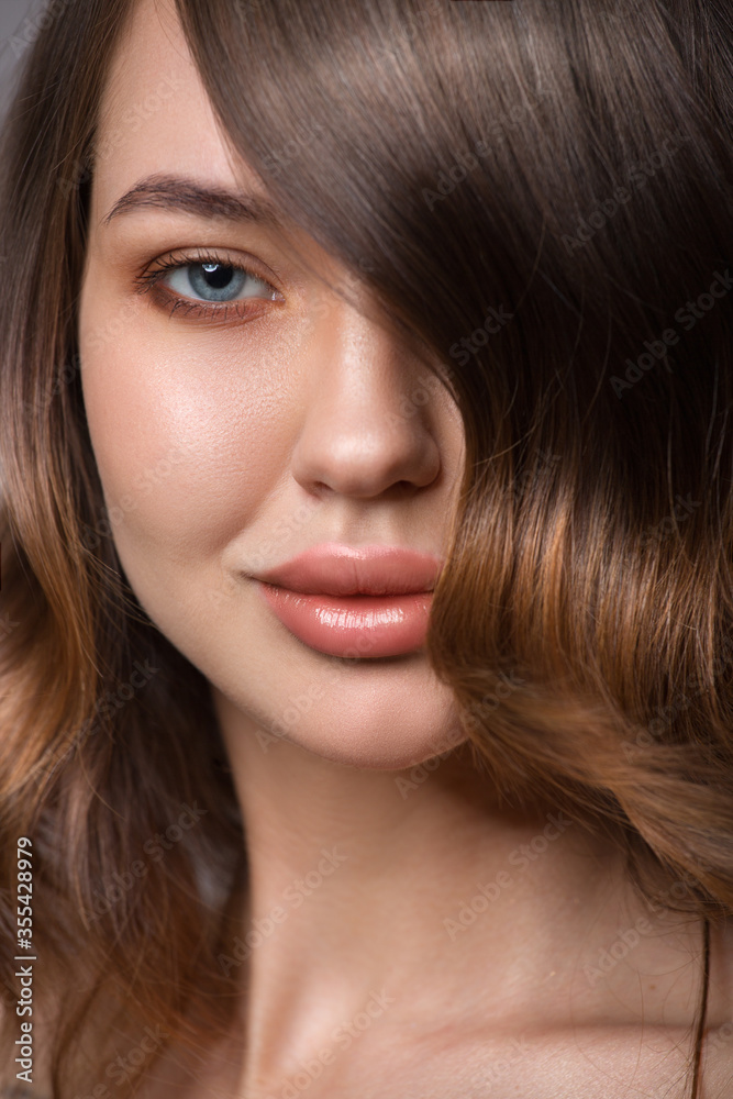 Close-up portrait of a woman. Luxurious hair covers part of her face Close-up portrait of a woman. Luxurious hair covers part of her face