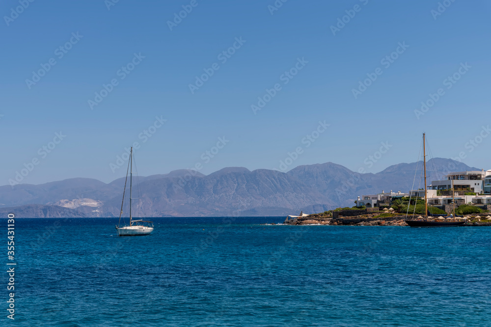 Summer sea view from coast with white yaht and mountains in background, Greece