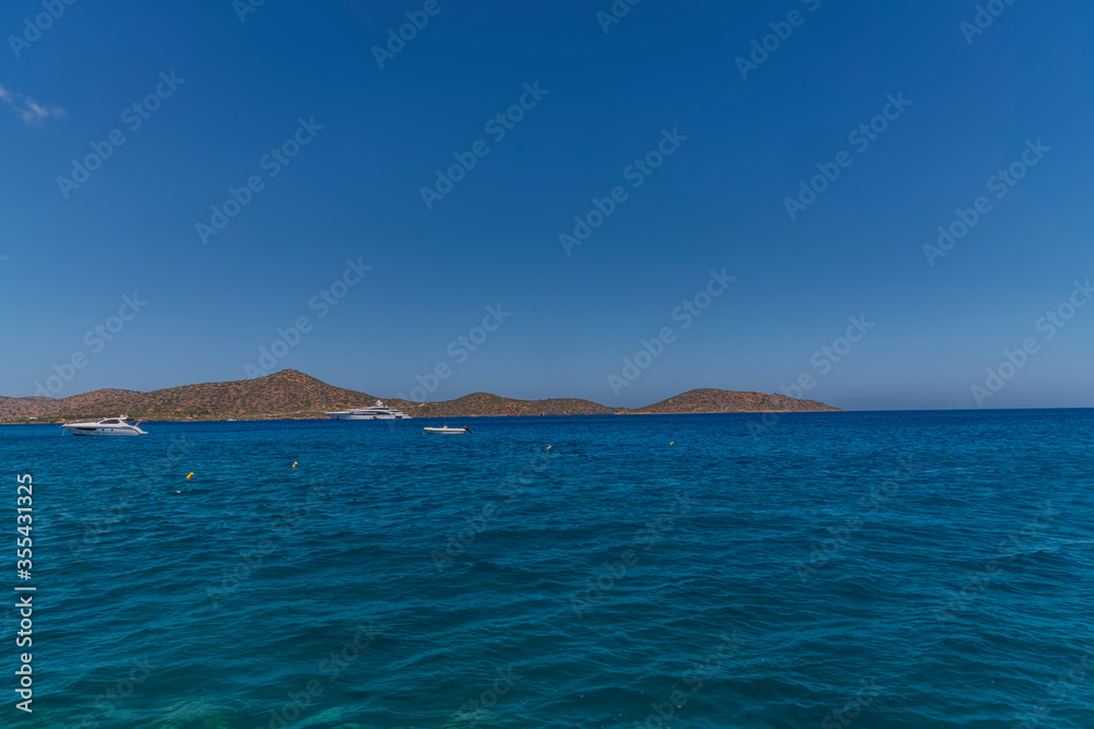 Summer sea view from coast with white yaht and mountains in background, Greece