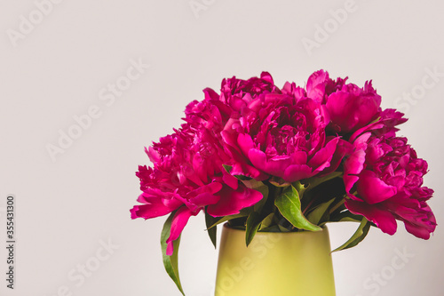 Fototapeta Naklejka Na Ścianę i Meble -  A bouquet of bright pink peonies in a green vase copy space. Blooming peonies. A bouquet of peonies as a gift.