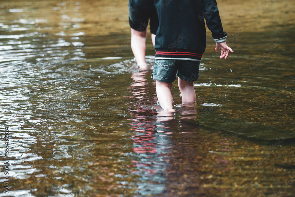Children playing outside in a shallow stream paddling in the water Children playing outside in a shallow stream paddling in the water