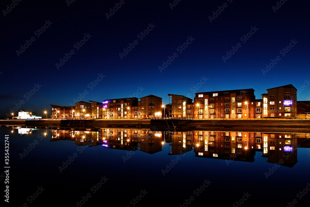 Quayside Apartment Building at night with reflections in the water. 