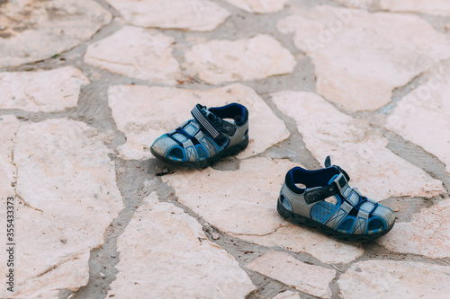 Father's day. Two blue children's sandals by the pool. Little boy took off his shoes before playing water pistols and left his shoes. © Yelyzaveta Kras